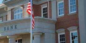 close up of bank exterior showing bank sign and American flag flying from flagpole