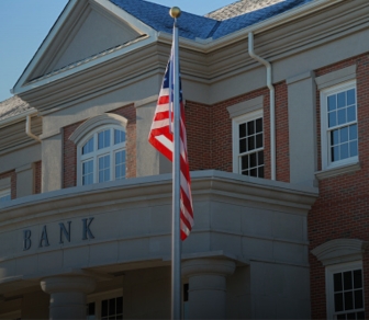 close up of bank exterior showing bank sign and American flag flying from flagpole